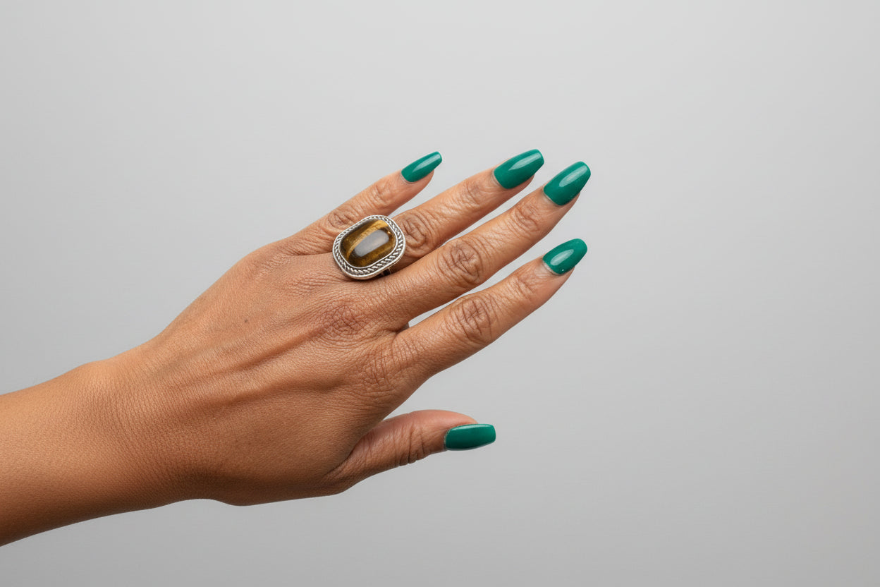 Hand with green nail polish wearing a large ring, with a blurred background