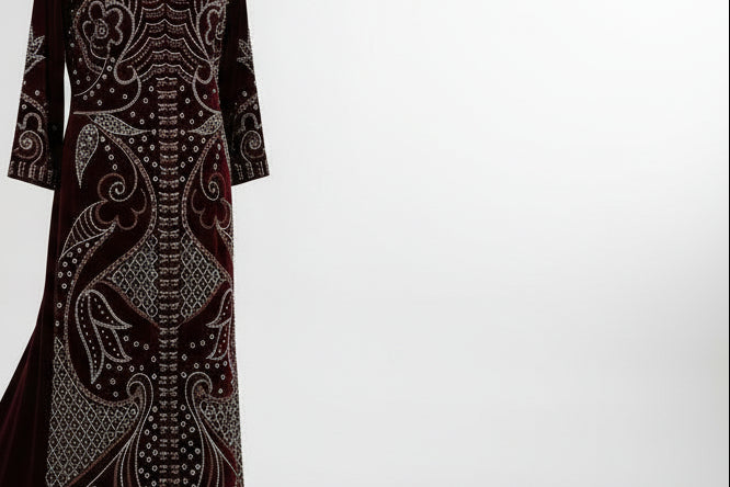 Long dark red dress with intricate patterns on a mannequin against a gray background